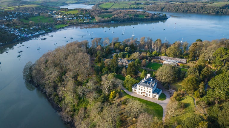 Aerial view of Greenway, Devon, the garden and woodland drifts down the hillside towards the Dart estuary.